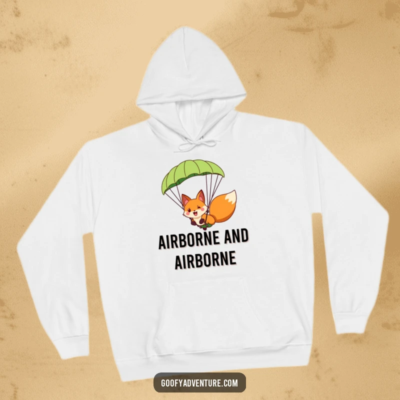 Funny fox character paragliding with a giant leaf parachute, depicted on a cozy hoodie, spreading joy and excitement.