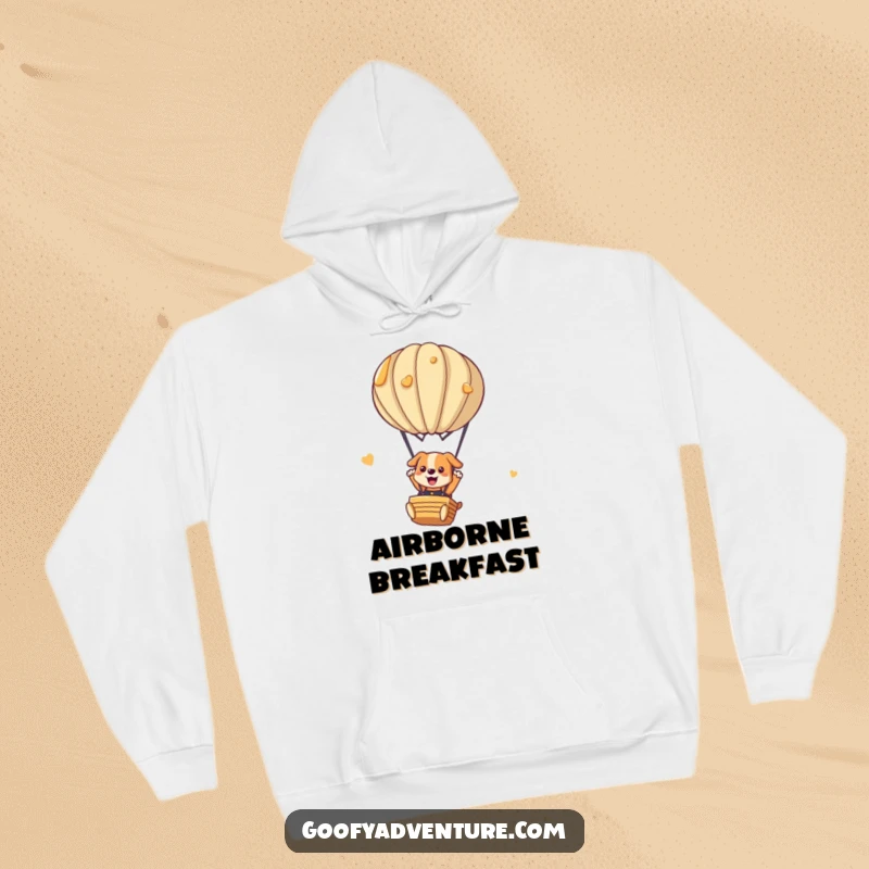 Funny dog hoodie with a playful dog parachuting from a whimsical hot air balloon made of pancakes. Cozy and humorous.